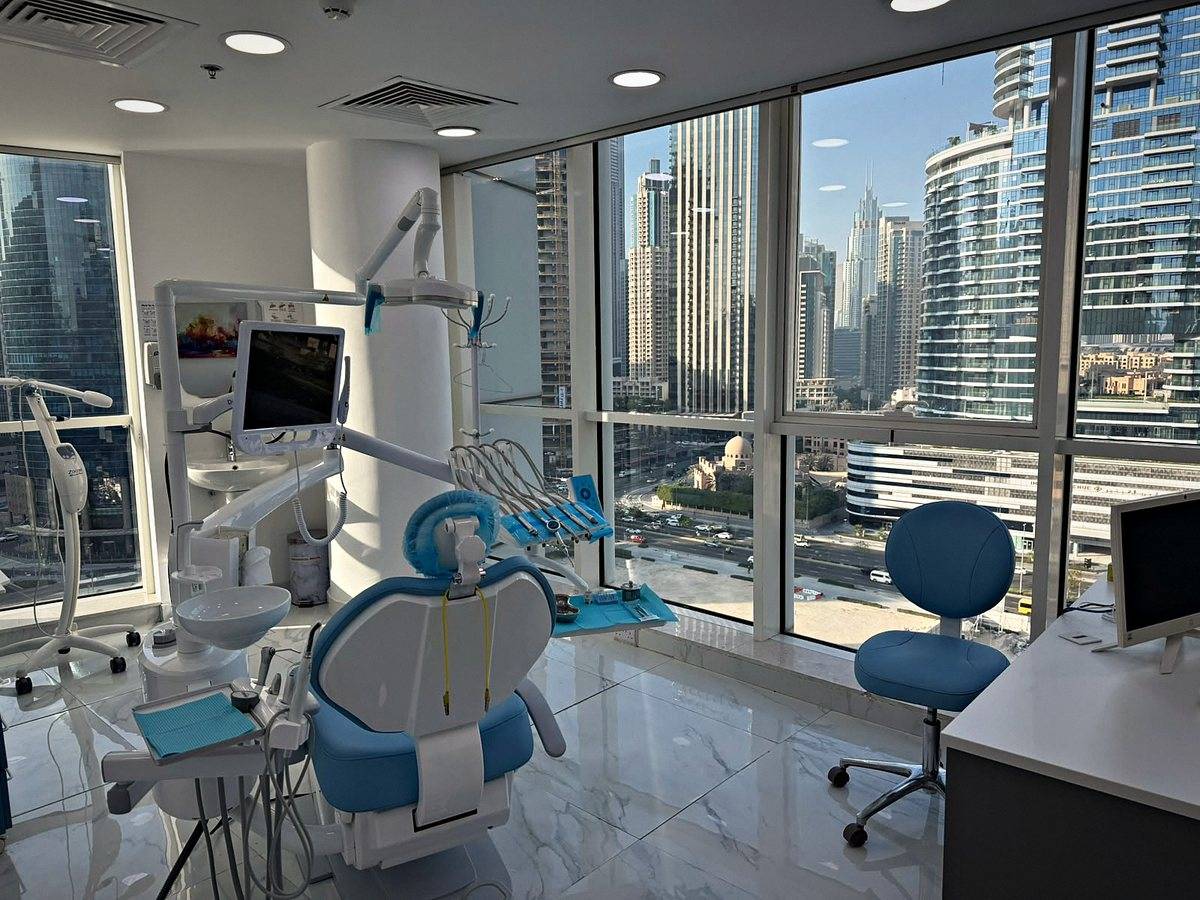 The blue dental chair at Murano Polyclinic, with the towers of Business Bay outside